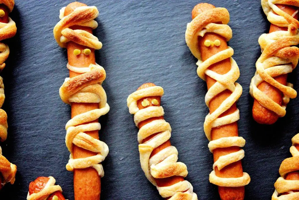 Close up of Halloween mummy hot dogs on a slate background