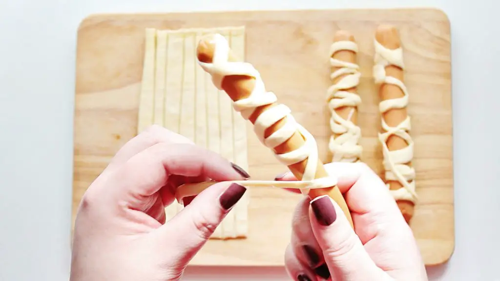 wrapping hot dogs with crescent roll strips to make mummy hot dogs