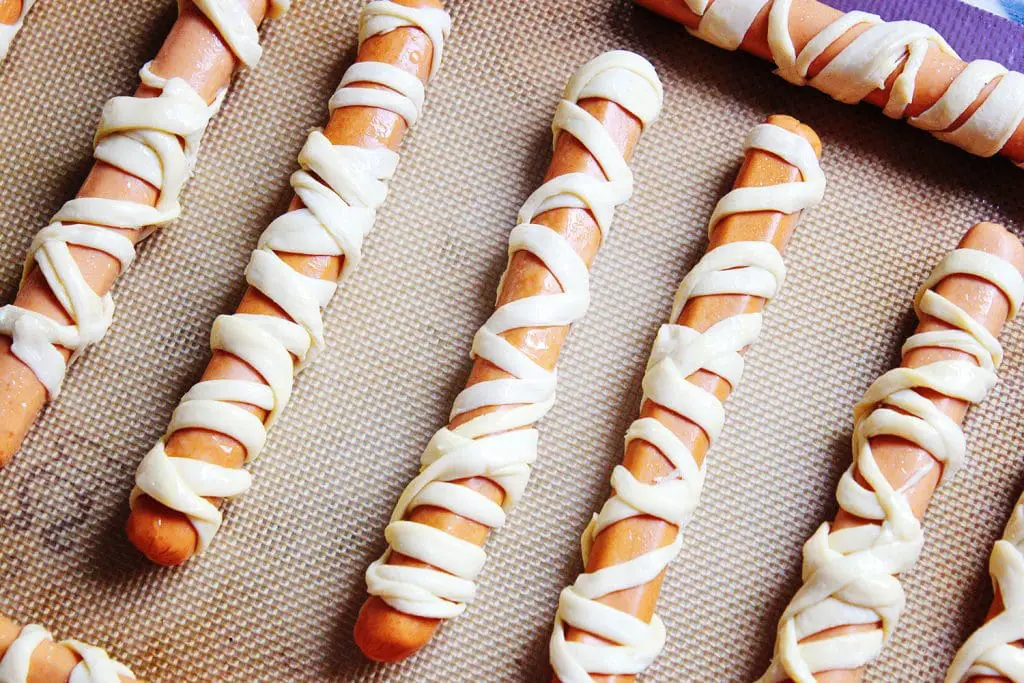 crescent roll wrapped mummy dogs waiting to go into the oven for baking