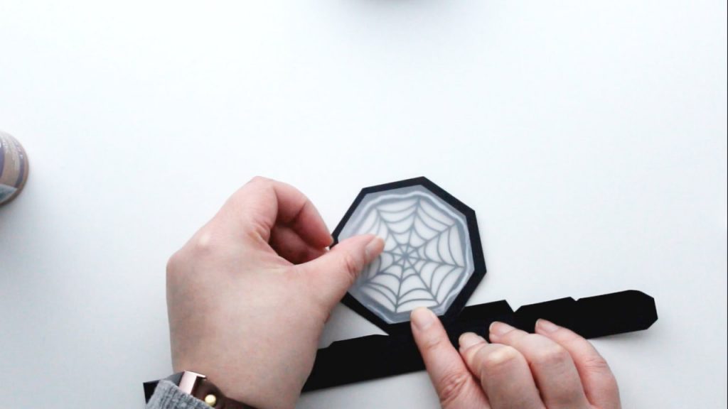 carefully place the backing piece over the spider web on the inside of the lid and smooth down