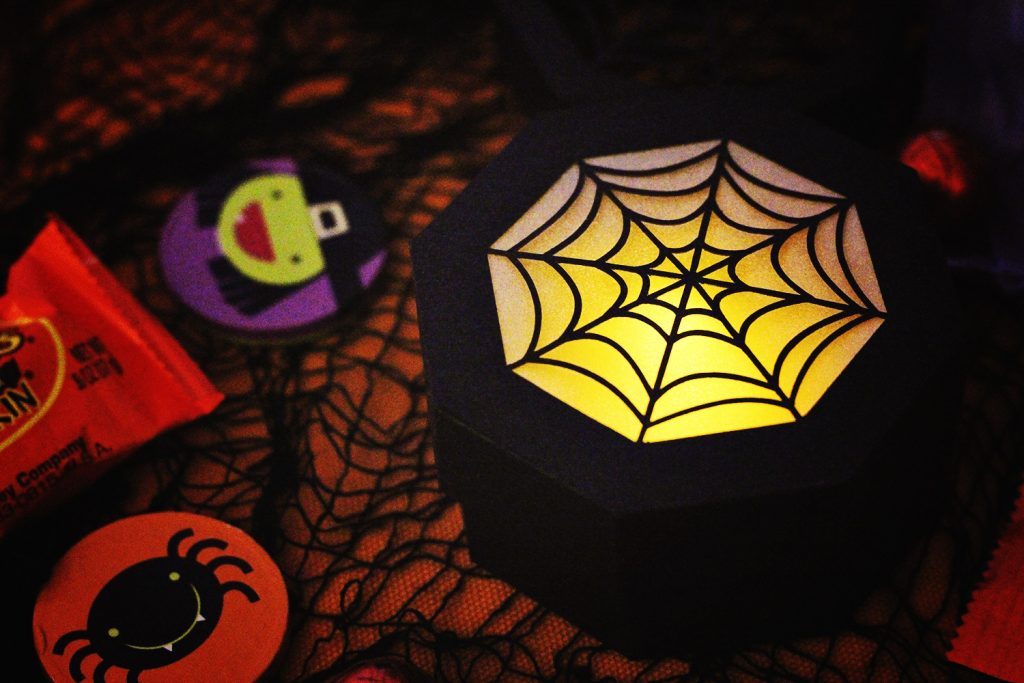 close up of the closed spider web treat box being used as a lantern with an led tea light inside for easy DIY halloween decor