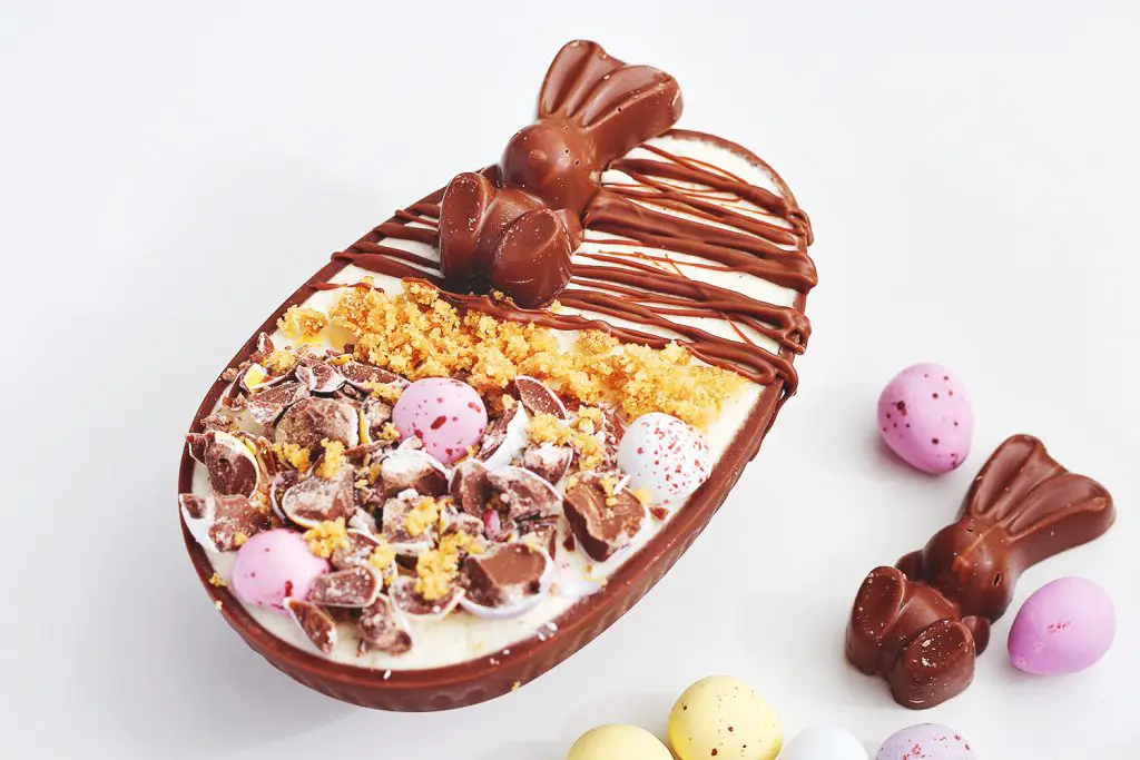 No-bake vanilla cheesecake in a chocolate egg shell decorated with Easter candy and melted chocolate